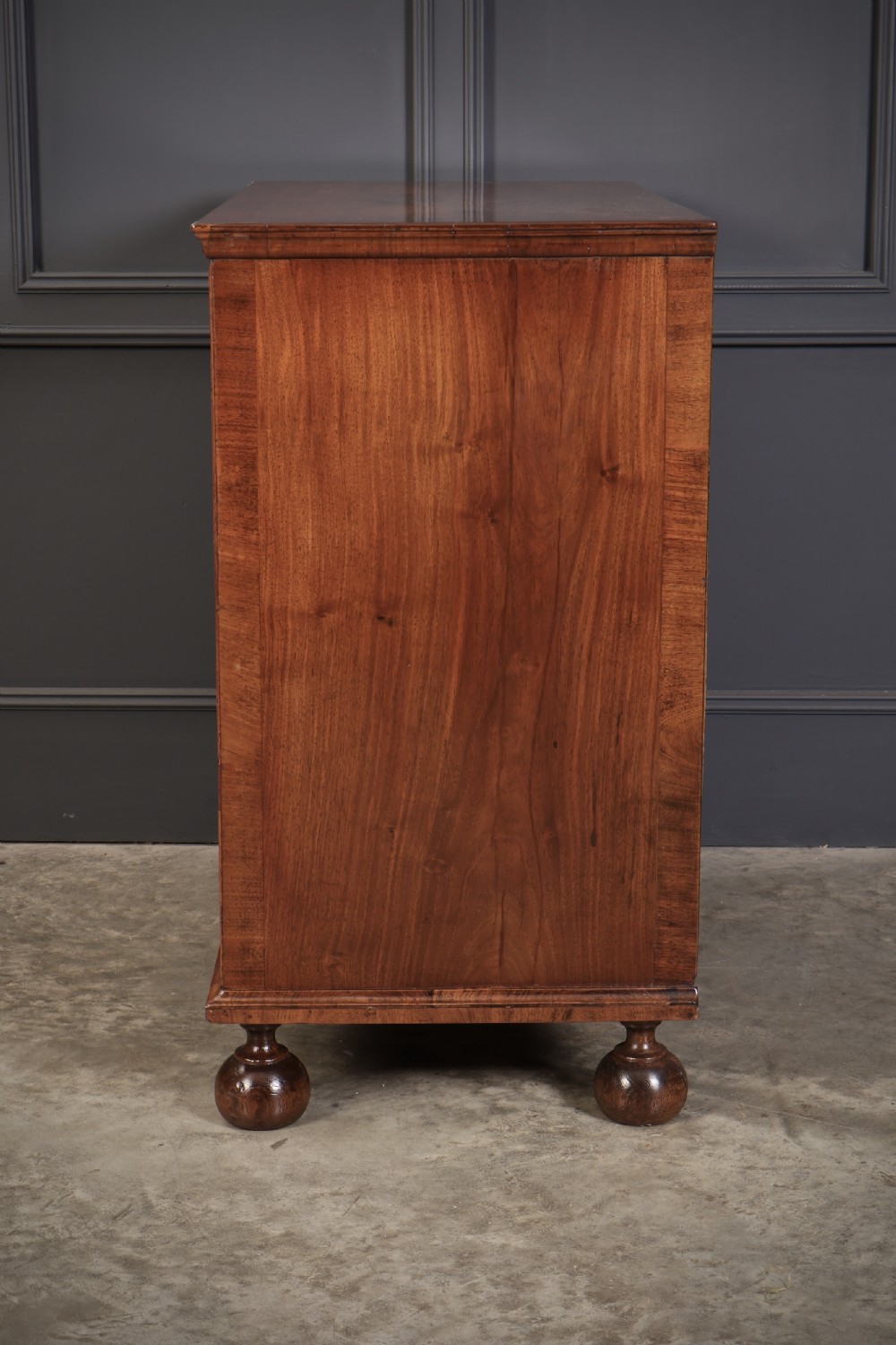 A Queen Anne style warm brown walnut chest of drawers featuring inlaid geometric top decoration, brass drop handles, keyhole escutcheons, and turned bun feet. View XII