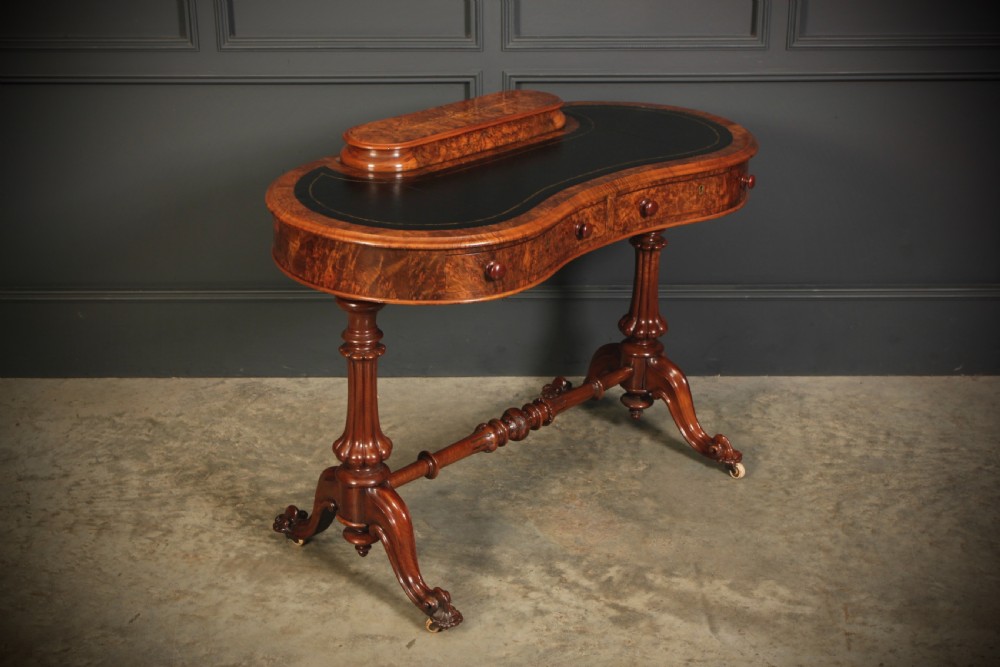 A Victorian burr walnut kidney-shaped writing table featuring a black leather insert, inlaid marquetry, raised caddy, frieze drawers, and carved legs on castors. View II