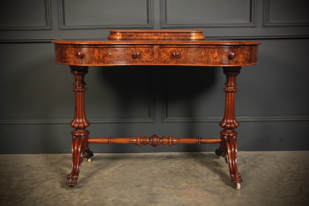 A Victorian burr walnut kidney-shaped writing table featuring a black leather insert, inlaid marquetry, raised caddy, frieze drawers, and carved legs on castors. View VII
