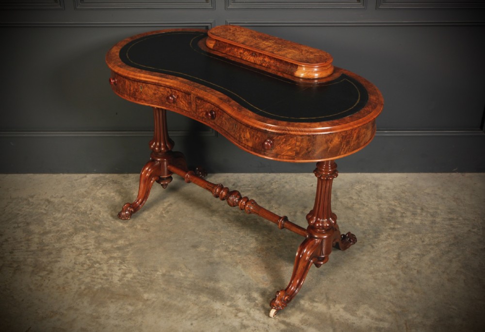 A Victorian burr walnut kidney-shaped writing table featuring a black leather insert, inlaid marquetry, raised caddy, frieze drawers, and carved legs on castors. View VIII