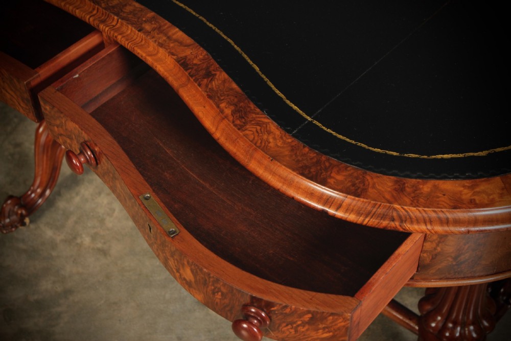 A Victorian burr walnut kidney-shaped writing table featuring a black leather insert, inlaid marquetry, raised caddy, frieze drawers, and carved legs on castors. View IX