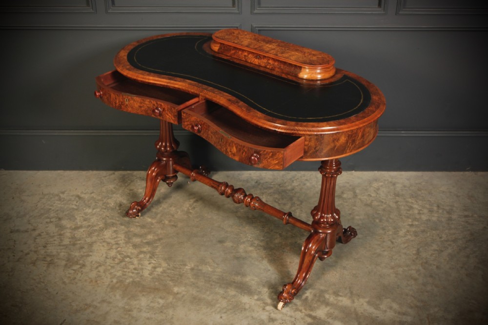 A Victorian burr walnut kidney-shaped writing table featuring a black leather insert, inlaid marquetry, raised caddy, frieze drawers, and carved legs on castors. View XII