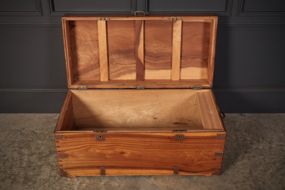 An antique camphor wood military campaign trunk with protective brass corner straps, flush brass fittings, and side carrying handles. View V