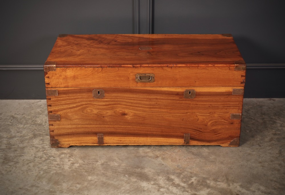 An antique camphor wood military campaign trunk with protective brass corner straps, flush brass fittings, and side carrying handles. View VI