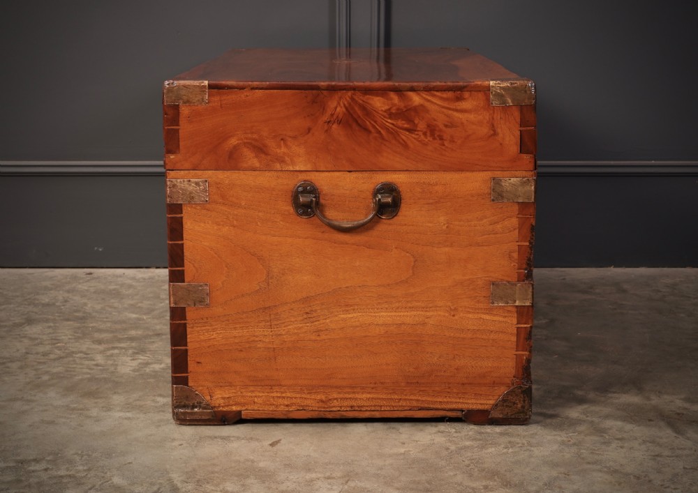An antique camphor wood military campaign trunk with protective brass corner straps, flush brass fittings, and side carrying handles. View IX