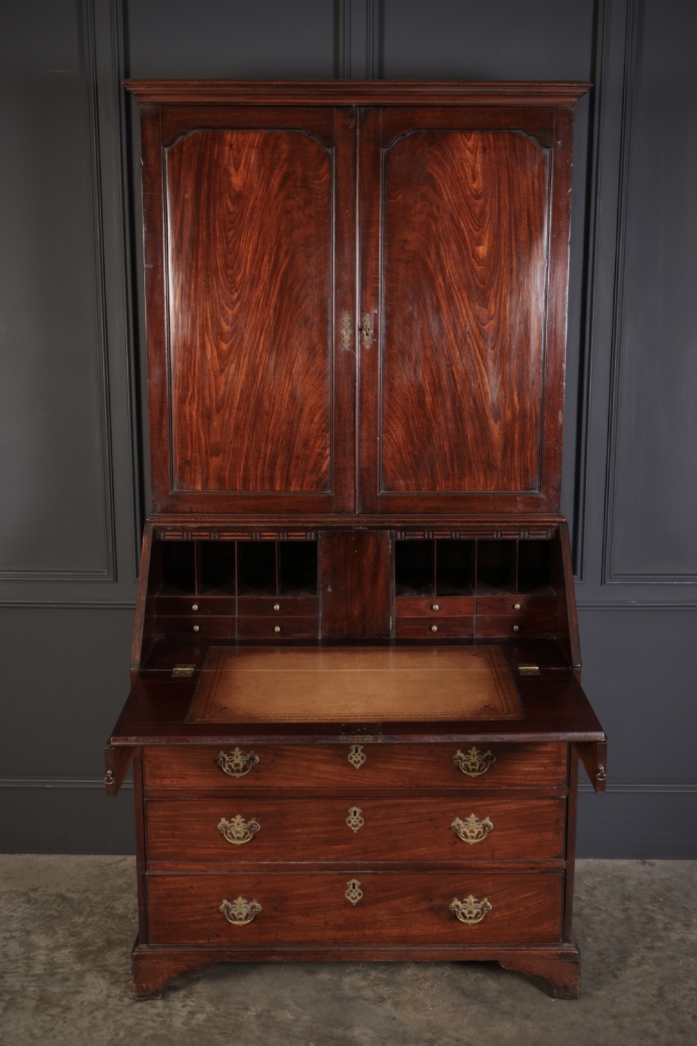 A Georgian rich mahogany bureau bookcase featuring a two-door upper cabinet, slant-front writing bureau, four drawers with brass handles, and bracket feet. View II