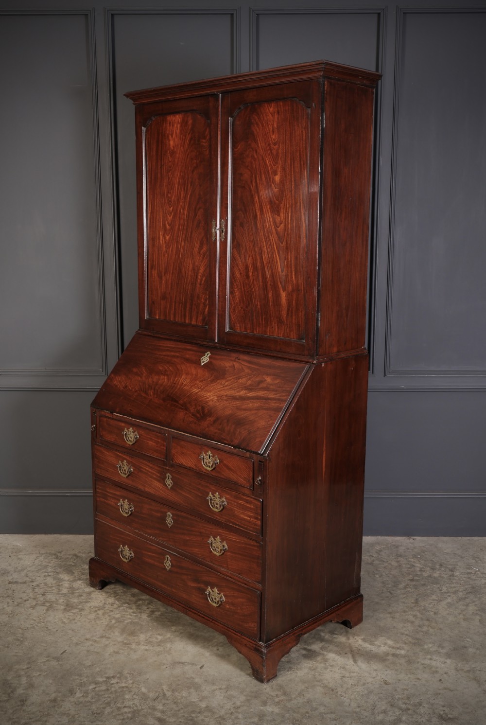 A Georgian rich mahogany bureau bookcase featuring a two-door upper cabinet, slant-front writing bureau, four drawers with brass handles, and bracket feet. View IX