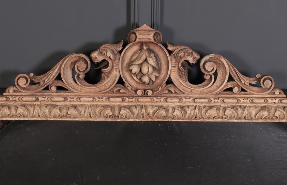 A large Victorian carved oak overmantel mirror featuring detailed carvings of mask heads, fruit garlands, and scrollwork around a rectangular glass plate. View III