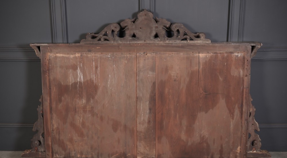 A large Victorian carved oak overmantel mirror featuring detailed carvings of mask heads, fruit garlands, and scrollwork around a rectangular glass plate. View IV