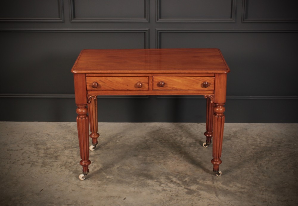A Victorian mahogany side table featuring two front drawers with wooden turned knobs and four reeded legs resting on ceramic castors. View III