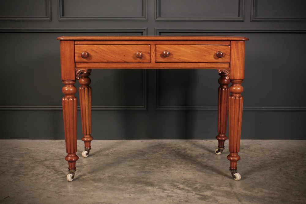 A Victorian mahogany side table featuring two front drawers with wooden turned knobs and four reeded legs resting on ceramic castors. View V