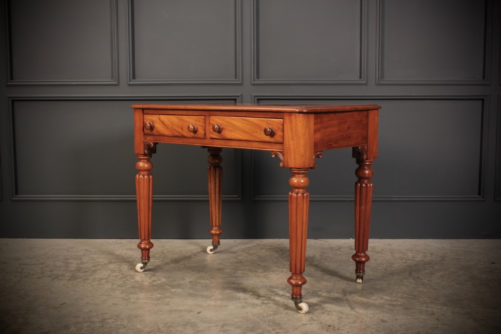 A Victorian mahogany side table featuring two front drawers with wooden turned knobs and four reeded legs resting on ceramic castors. View VII