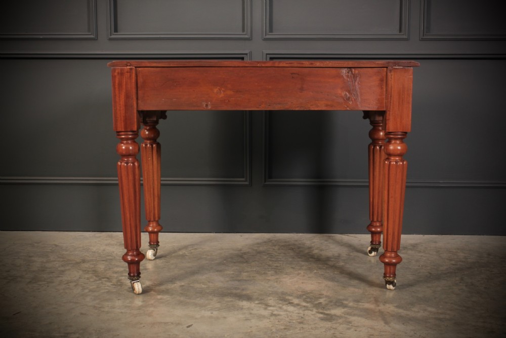 A Victorian mahogany side table featuring two front drawers with wooden turned knobs and four reeded legs resting on ceramic castors. View VIII