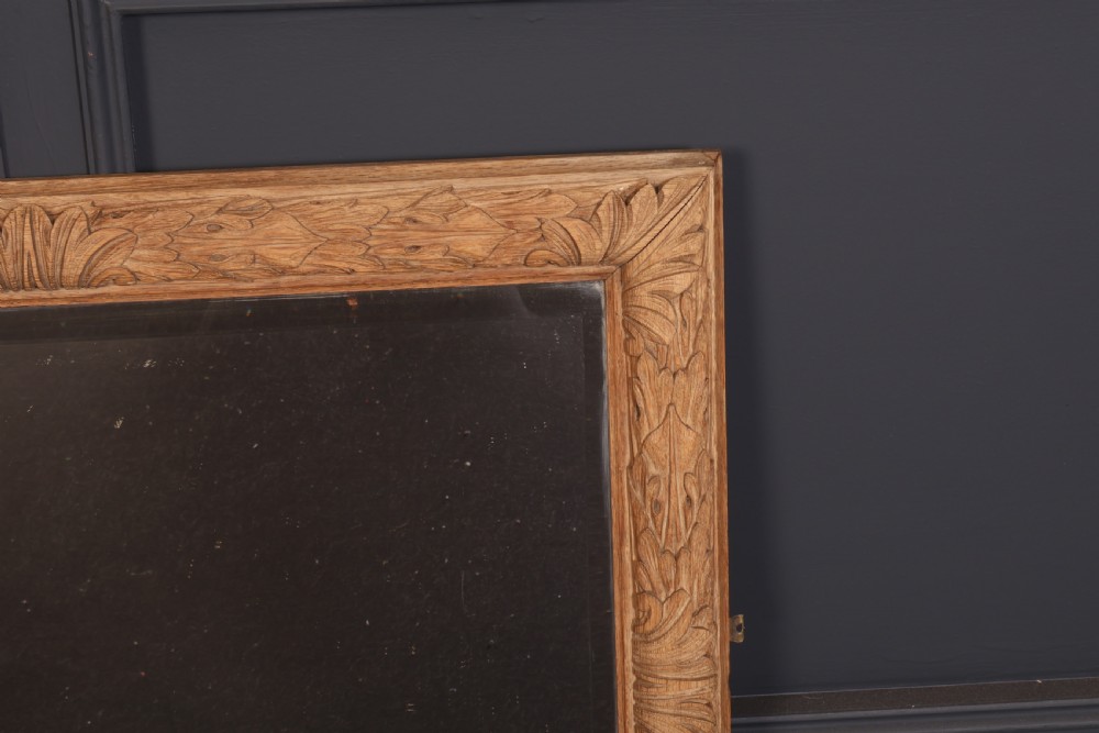 A rectangular wall mirror featuring a carved oak frame with relief acanthus leaf motifs surrounding a central reflective glass panel. View V