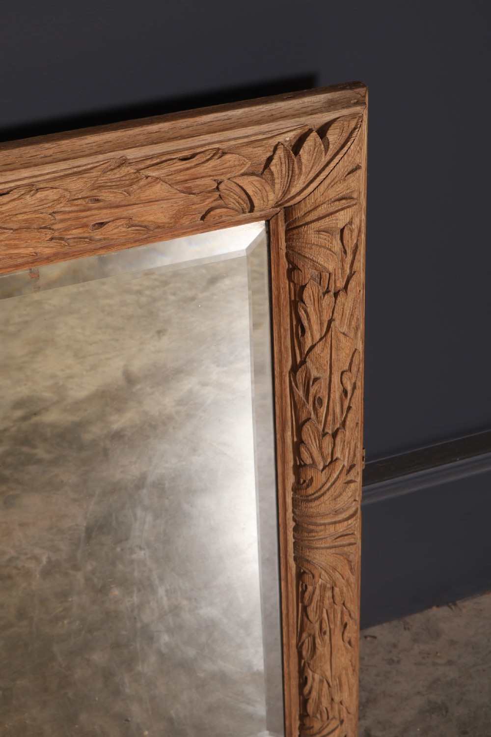 A rectangular wall mirror featuring a carved oak frame with relief acanthus leaf motifs surrounding a central reflective glass panel. View VII