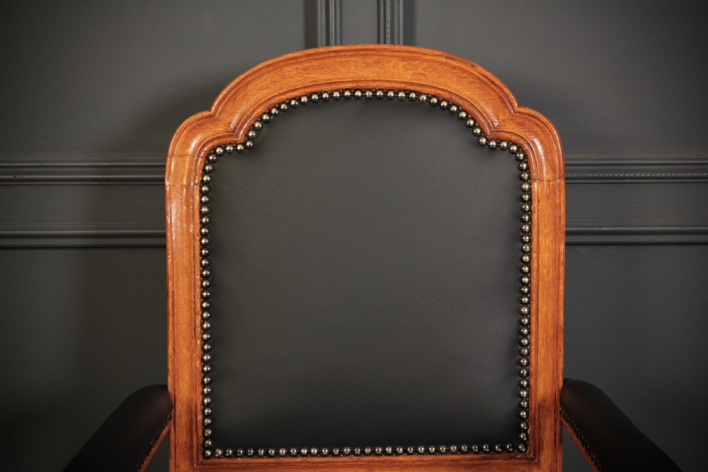 A pair of Victorian oak desk armchairs upholstered in black leather with brass stud trimming and turned legs on castors. View IX