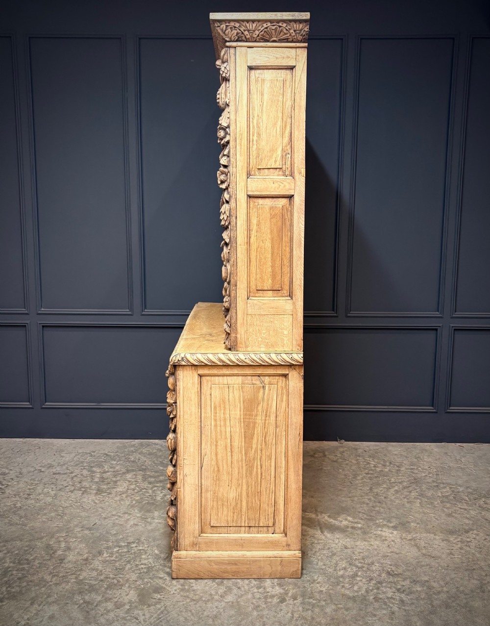 A large two-tier bleached oak open bookcase featuring heavily carved floral pilasters, open adjustable shelves, and a lower cabinet with relief-carved doors. View VIII