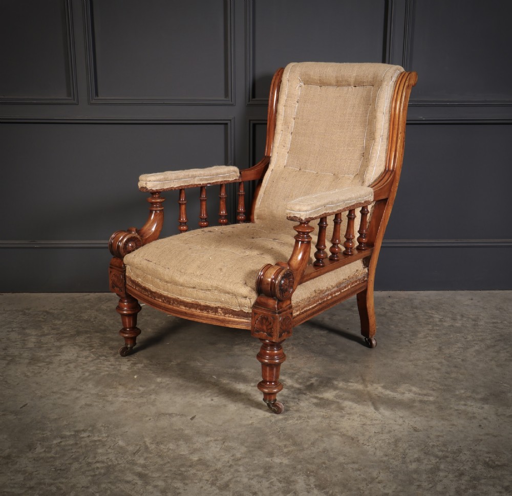 Victorian walnut library armchair with carved scroll arms, turned spindle supports, turned front legs on castors, and hessian lining. View VI