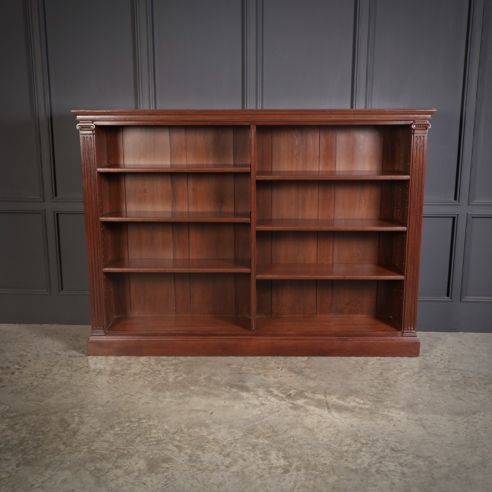 A large Victorian open oak bookcase featuring two wide bays with adjustable shelves, fluted pilasters, and a solid plinth base. View V