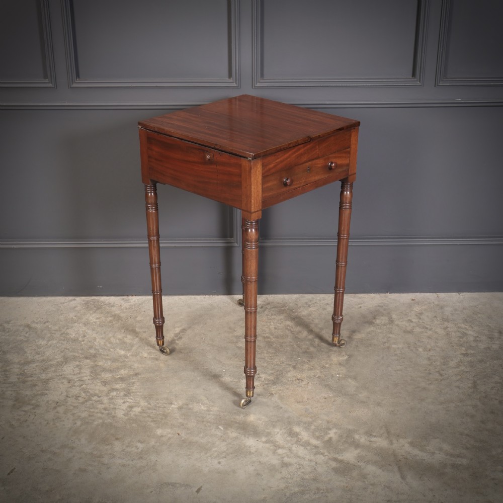An antique Regency mahogany writing table featuring an adjustable leather-lined ratcheted reading slope, drop side flaps, a single drawer, and ring-turned legs with brass castors. View X