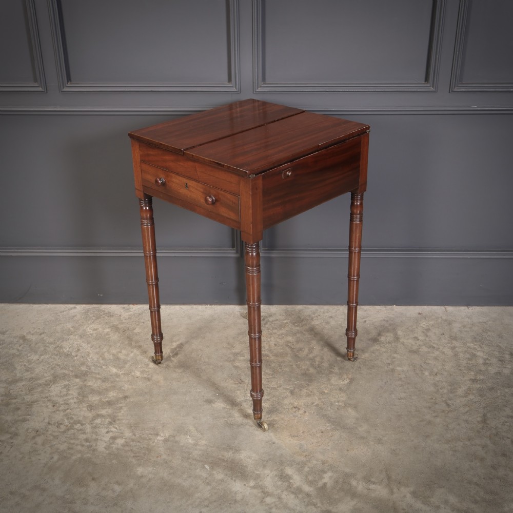 An antique Regency mahogany writing table featuring an adjustable leather-lined ratcheted reading slope, drop side flaps, a single drawer, and ring-turned legs with brass castors. View V