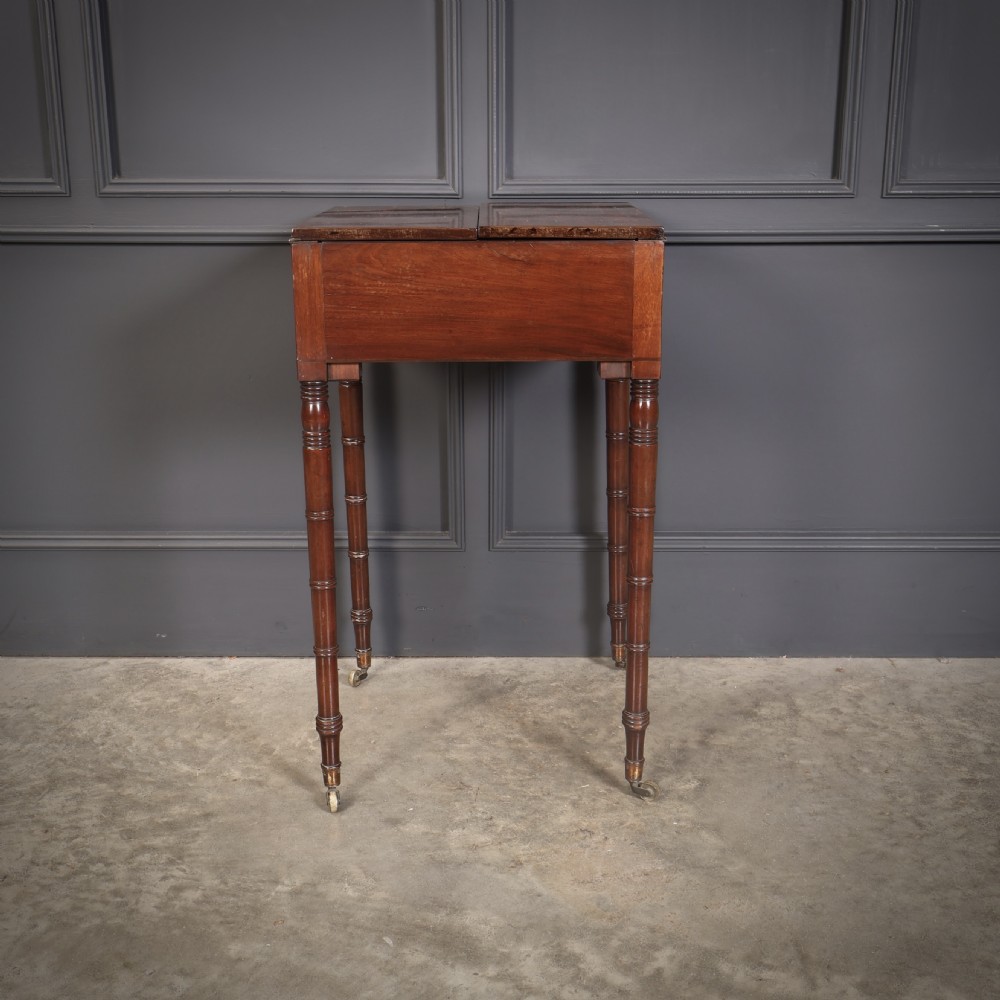 An antique Regency mahogany writing table featuring an adjustable leather-lined ratcheted reading slope, drop side flaps, a single drawer, and ring-turned legs with brass castors. View VII