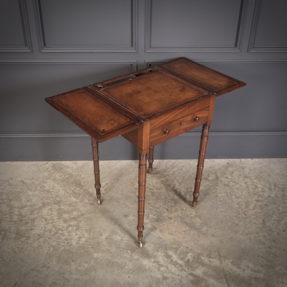 An antique Regency mahogany writing table featuring an adjustable leather-lined ratcheted reading slope, drop side flaps, a single drawer, and ring-turned legs with brass castors. View IX