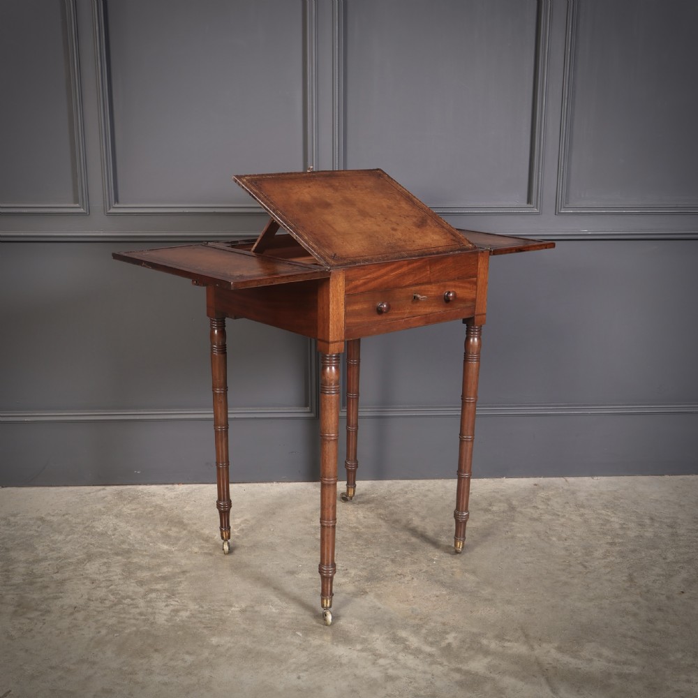 An antique Regency mahogany writing table featuring an adjustable leather-lined ratcheted reading slope, drop side flaps, a single drawer, and ring-turned legs with brass castors. View XI