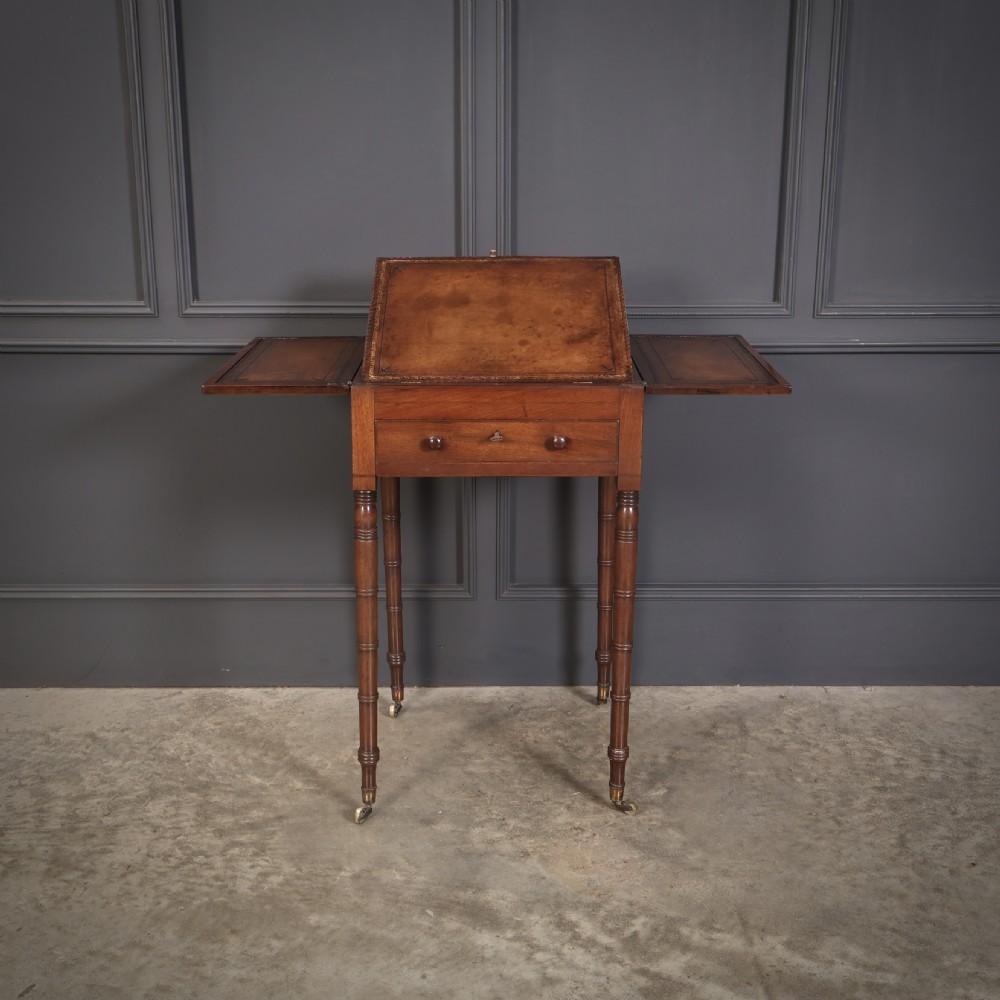 An antique Regency mahogany writing table featuring an adjustable leather-lined ratcheted reading slope, drop side flaps, a single drawer, and ring-turned legs with brass castors. View XII