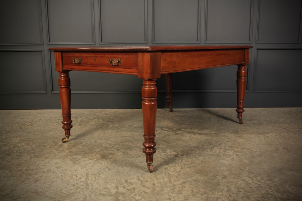 A Victorian mahogany writing table with a red leather inset surface, turned legs, and brass castors. View III