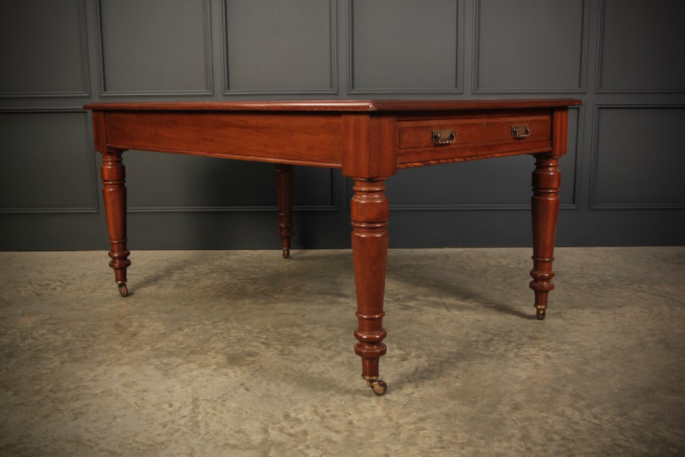 A Victorian mahogany writing table with a red leather inset surface, turned legs, and brass castors. View VI