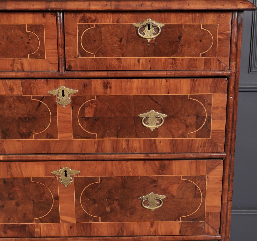 A William and Mary period chest of drawers with decorative oyster veneering, stringing inlay, brass teardrop handles, and turned bun feet. View VI