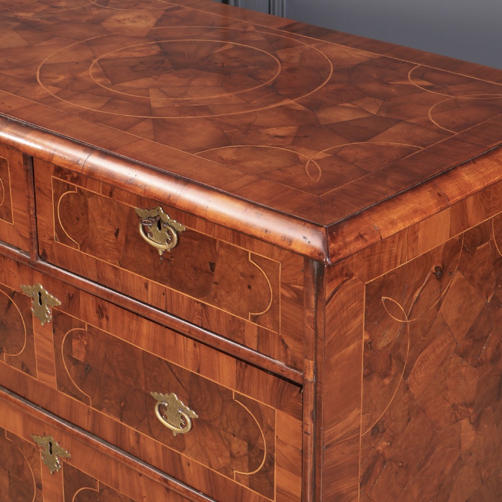 A William and Mary period chest of drawers with decorative oyster veneering, stringing inlay, brass teardrop handles, and turned bun feet. View X