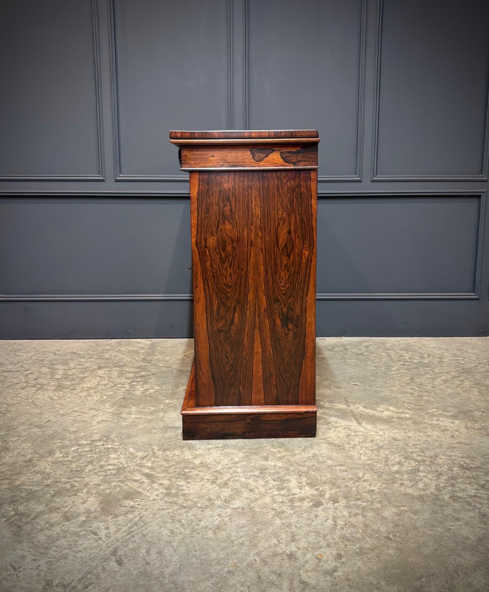 A William IV rosewood side cabinet with twin arch-topped mirrored doors, carved foliage details along the frieze, and a sturdy plinth base. View VI