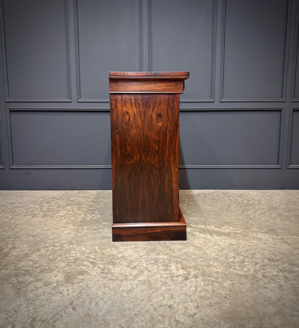 A William IV rosewood side cabinet with twin arch-topped mirrored doors, carved foliage details along the frieze, and a sturdy plinth base. View XIII