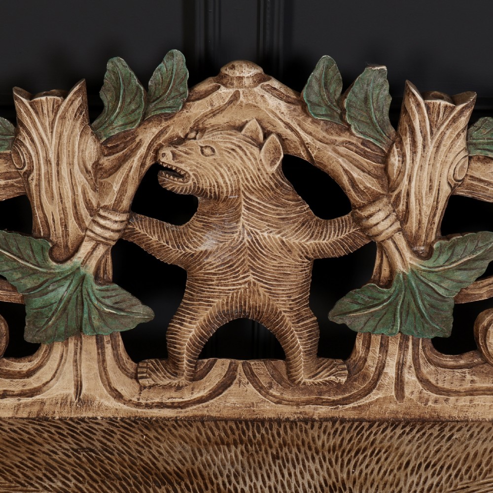 A carved light brown wooden two-seat bench featuring full-standing bear supports on each side and a central carved bear with green painted leaves on the backrest. View II