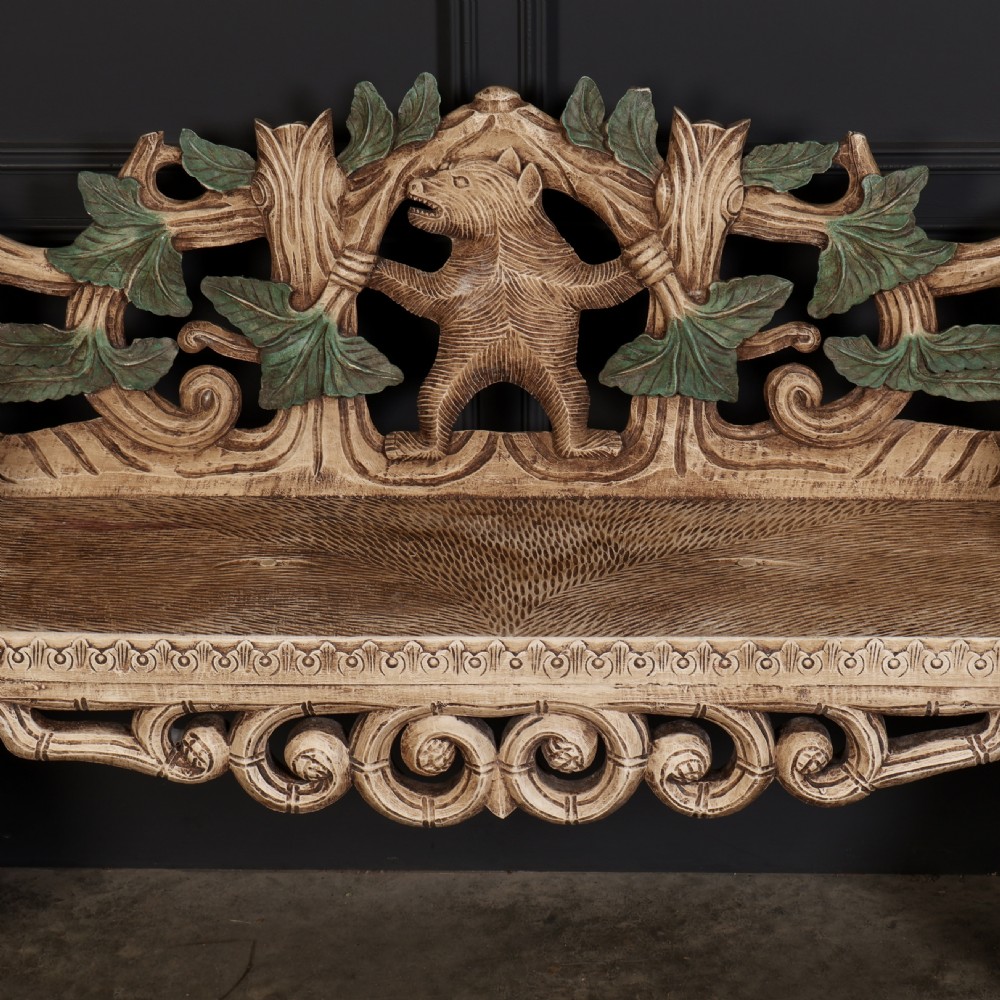 A carved light brown wooden two-seat bench featuring full-standing bear supports on each side and a central carved bear with green painted leaves on the backrest. View III