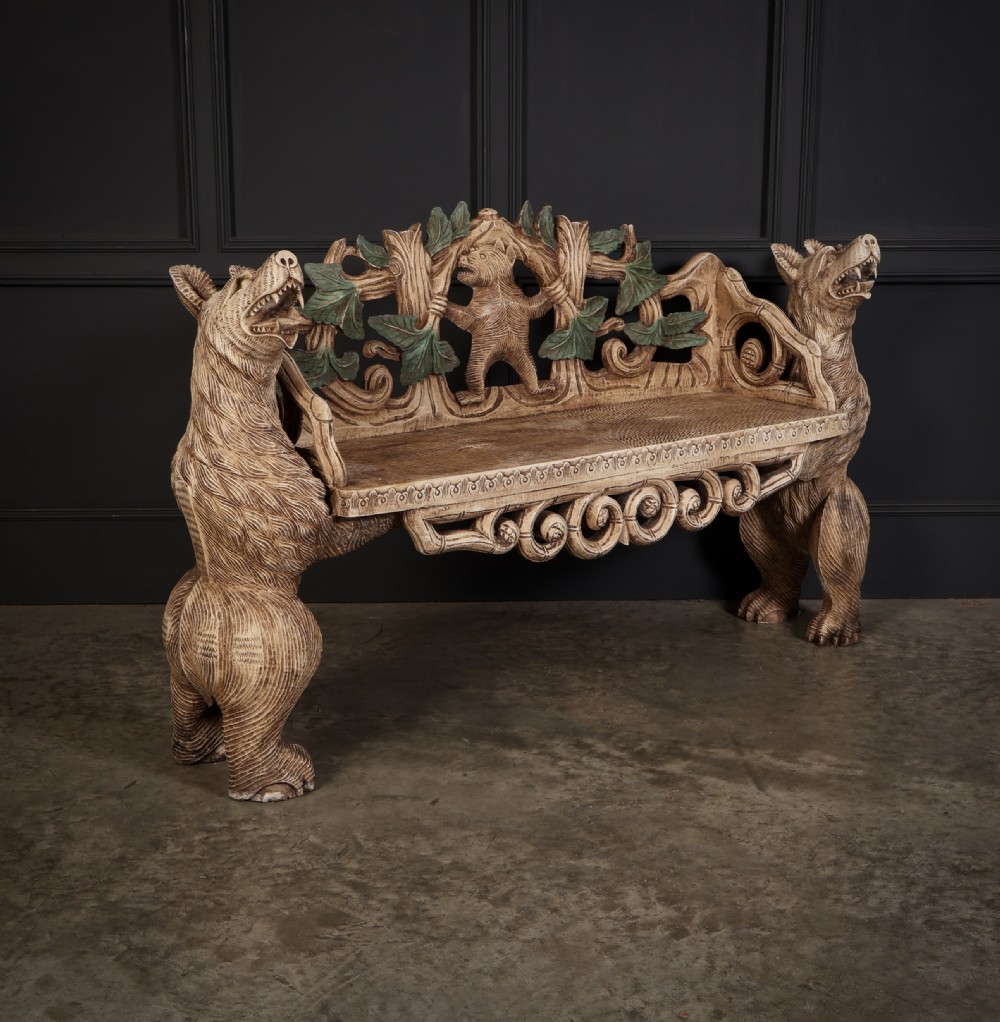 A carved light brown wooden two-seat bench featuring full-standing bear supports on each side and a central carved bear with green painted leaves on the backrest. View VI