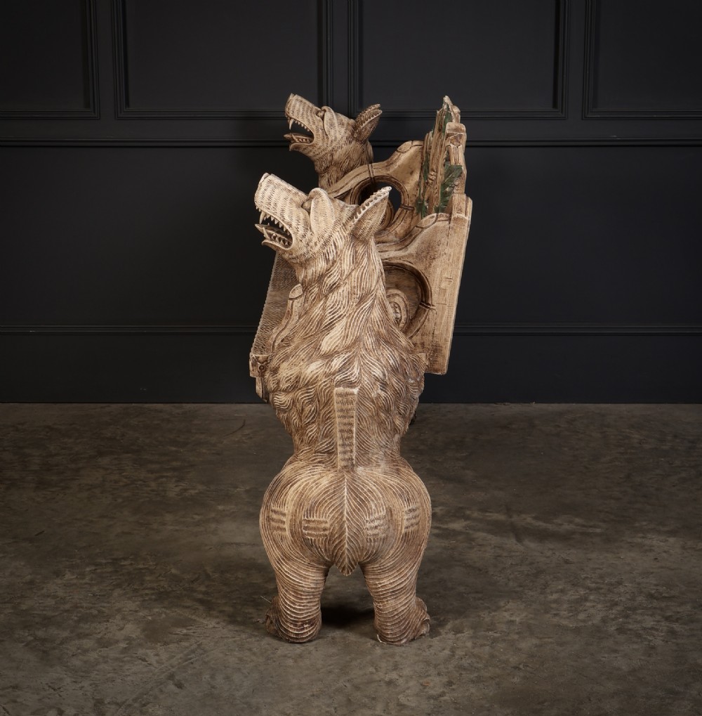 A carved light brown wooden two-seat bench featuring full-standing bear supports on each side and a central carved bear with green painted leaves on the backrest. View X