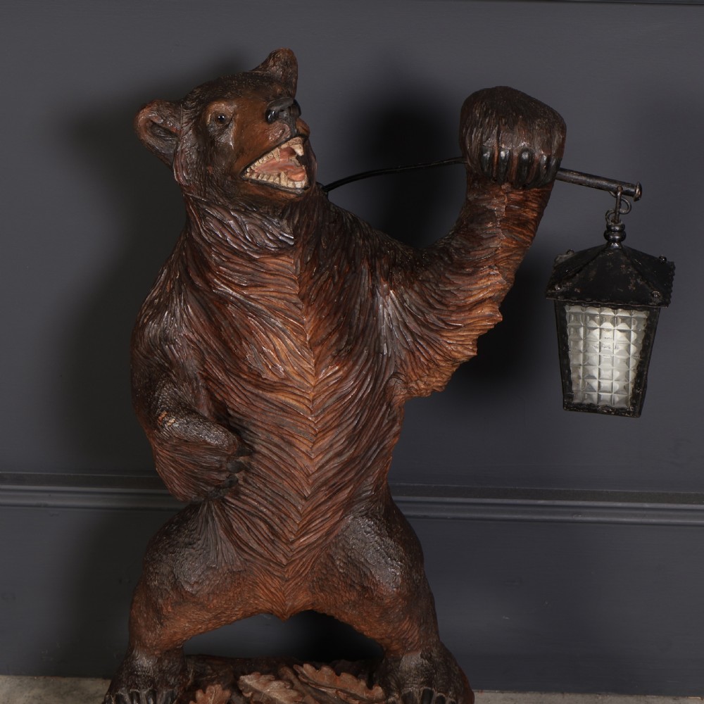A hand-carved wooden standing bear holding a metal lantern fixture on a carved timber base. View III