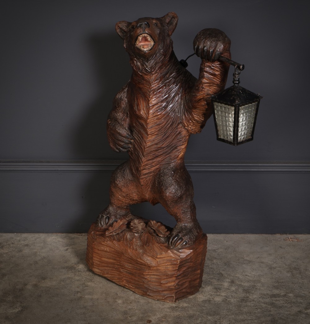A hand-carved wooden standing bear holding a metal lantern fixture on a carved timber base. View V