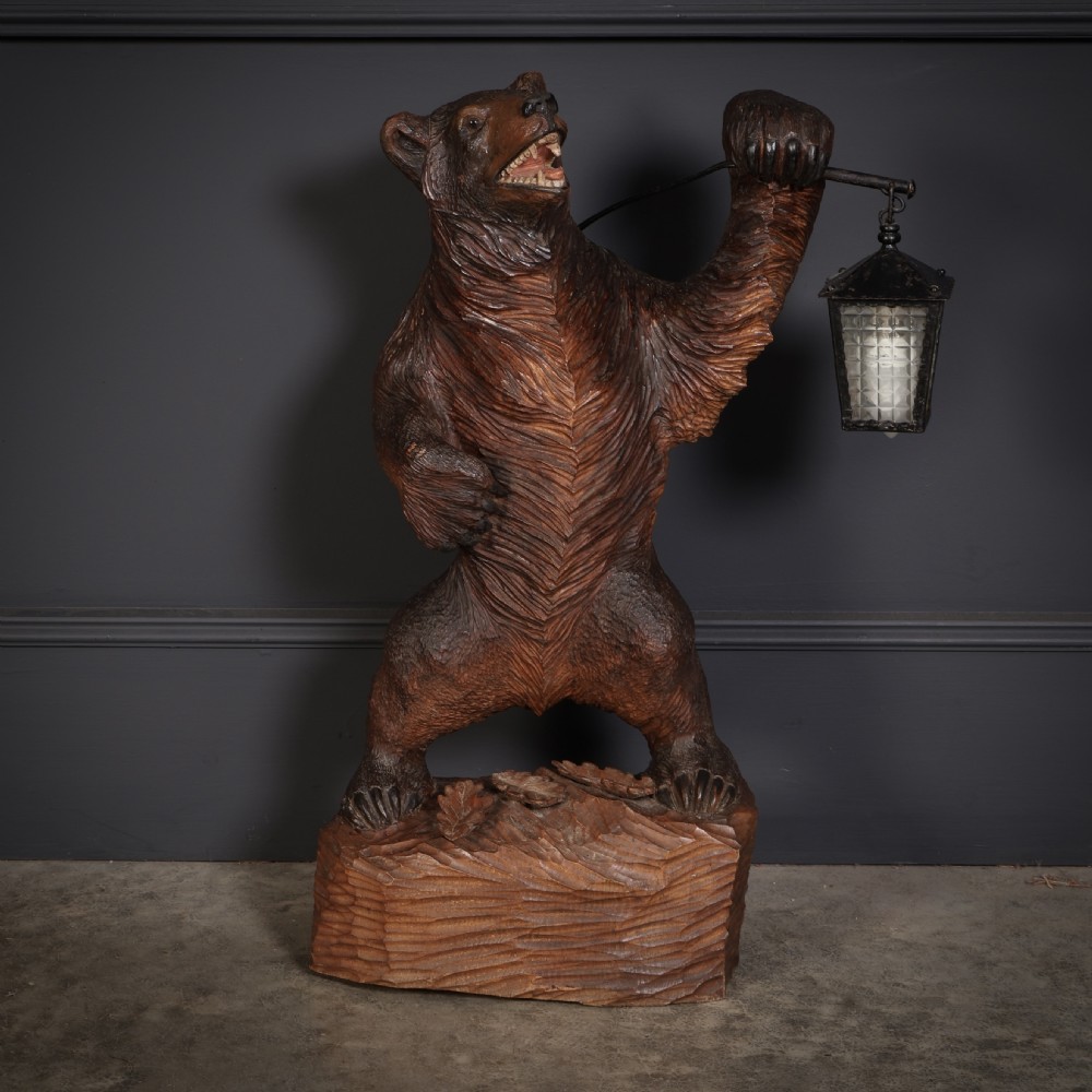 A hand-carved wooden standing bear holding a metal lantern fixture on a carved timber base. View VI
