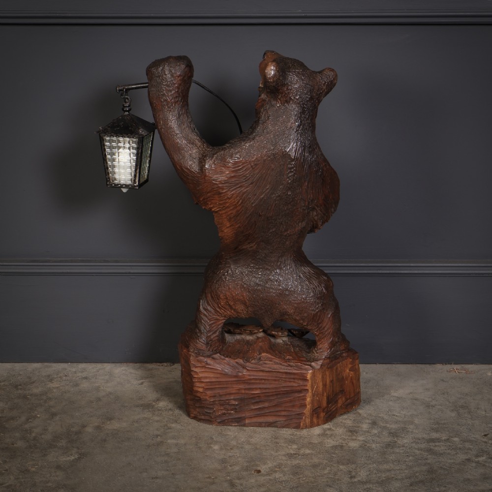 A hand-carved wooden standing bear holding a metal lantern fixture on a carved timber base. View VII