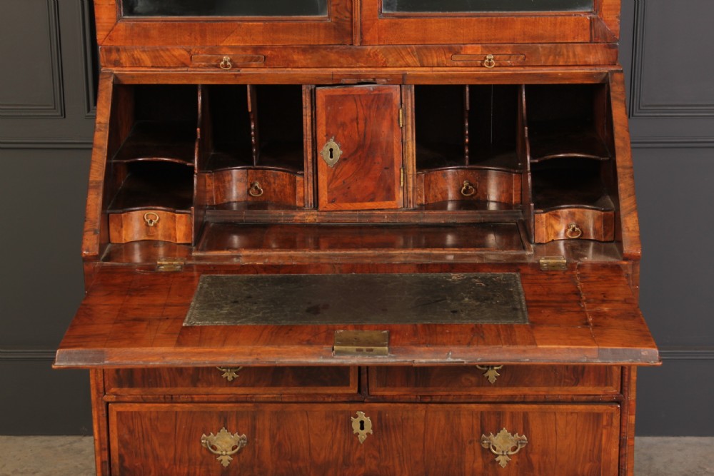 An 18th-century walnut bureau bookcase featuring a double-domed upper cabinet with arched mirrored doors set above a slant-front writing desk and drawers. View V