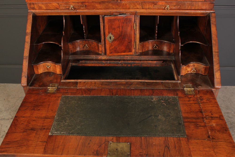 An 18th-century walnut bureau bookcase featuring a double-domed upper cabinet with arched mirrored doors set above a slant-front writing desk and drawers. View VI