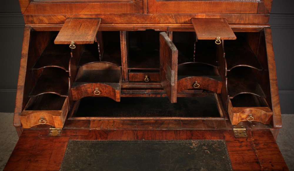 An 18th-century walnut bureau bookcase featuring a double-domed upper cabinet with arched mirrored doors set above a slant-front writing desk and drawers. View IX