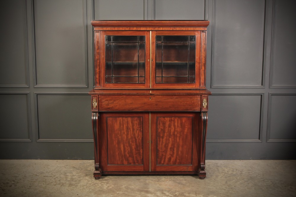 A Regency flame mahogany secretaire bookcase featuring a glazed upper display cabinet above a fall-front desk drawer and lower cupboard with curved pilasters. View II