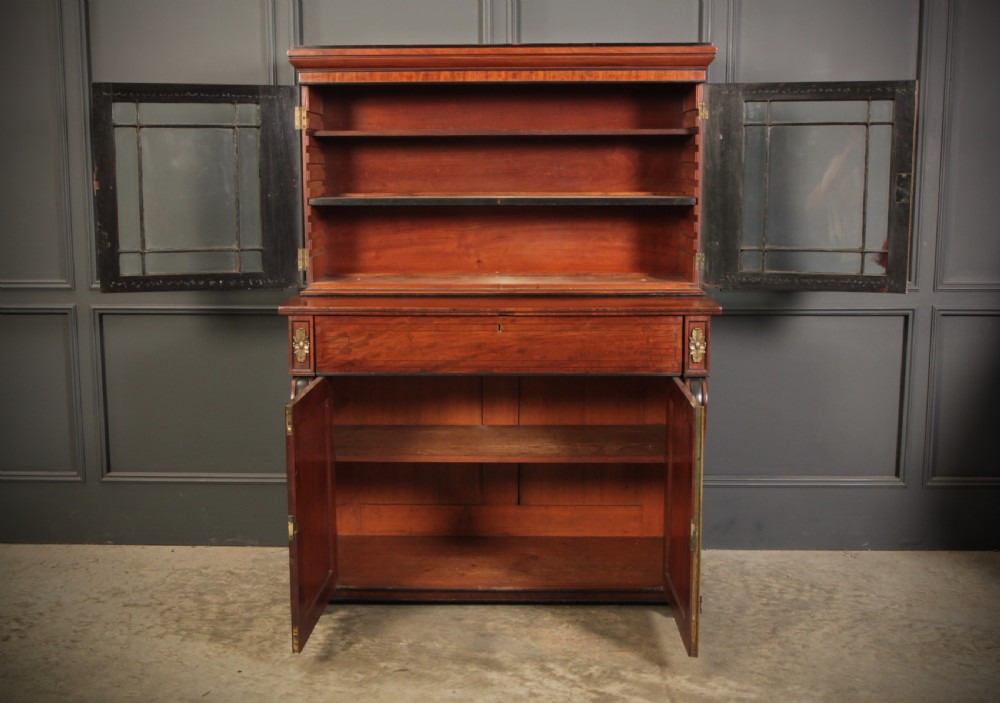 A Regency flame mahogany secretaire bookcase featuring a glazed upper display cabinet above a fall-front desk drawer and lower cupboard with curved pilasters. View III
