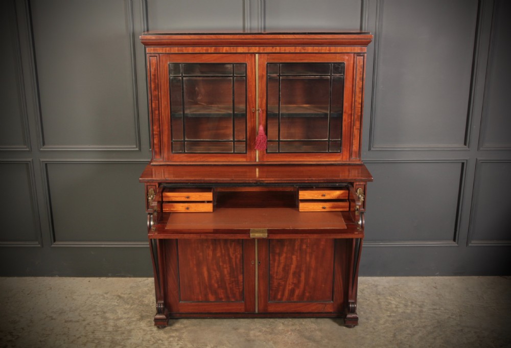 A Regency flame mahogany secretaire bookcase featuring a glazed upper display cabinet above a fall-front desk drawer and lower cupboard with curved pilasters. View V