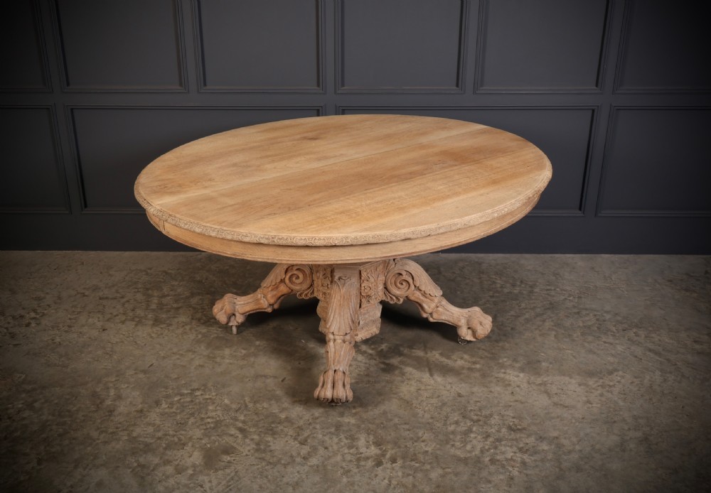 An oval bleached oak centre table featuring an intricately carved pedestal base with scroll legs and paw feet. View II